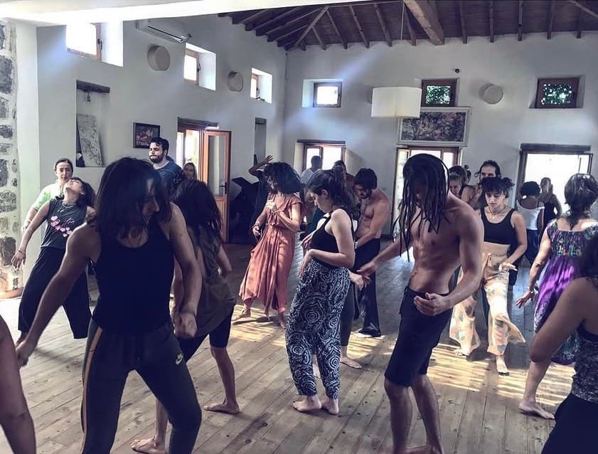Ahşap zeminli salonda bir grup 5Rhythms seansında dans ederken