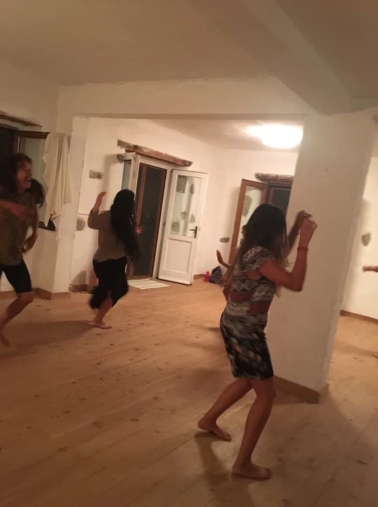 Akşam, beyaz duvarlı salonda yalınayak dans eden katılımcılar