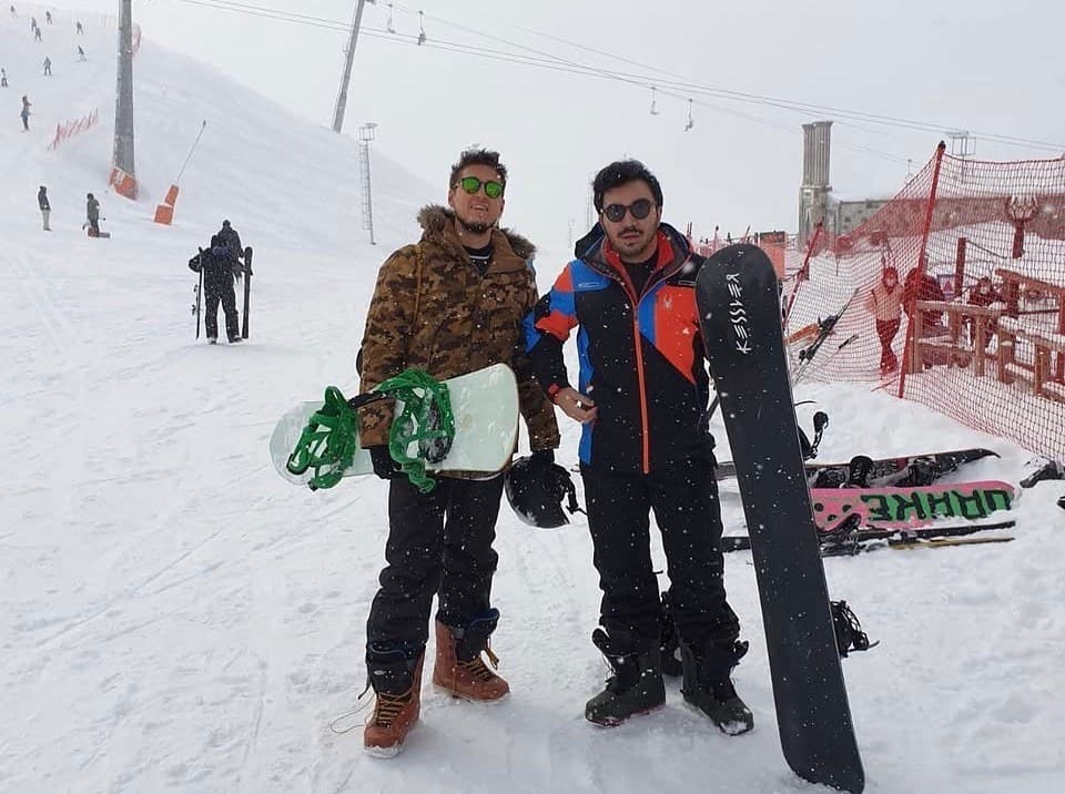 Karlı pistte ellerinde snowboard'larla iki kişi