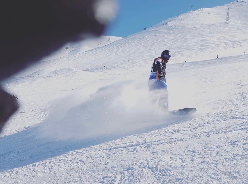 Pistte kar savurarak dönüş yapan bir snowboardcu