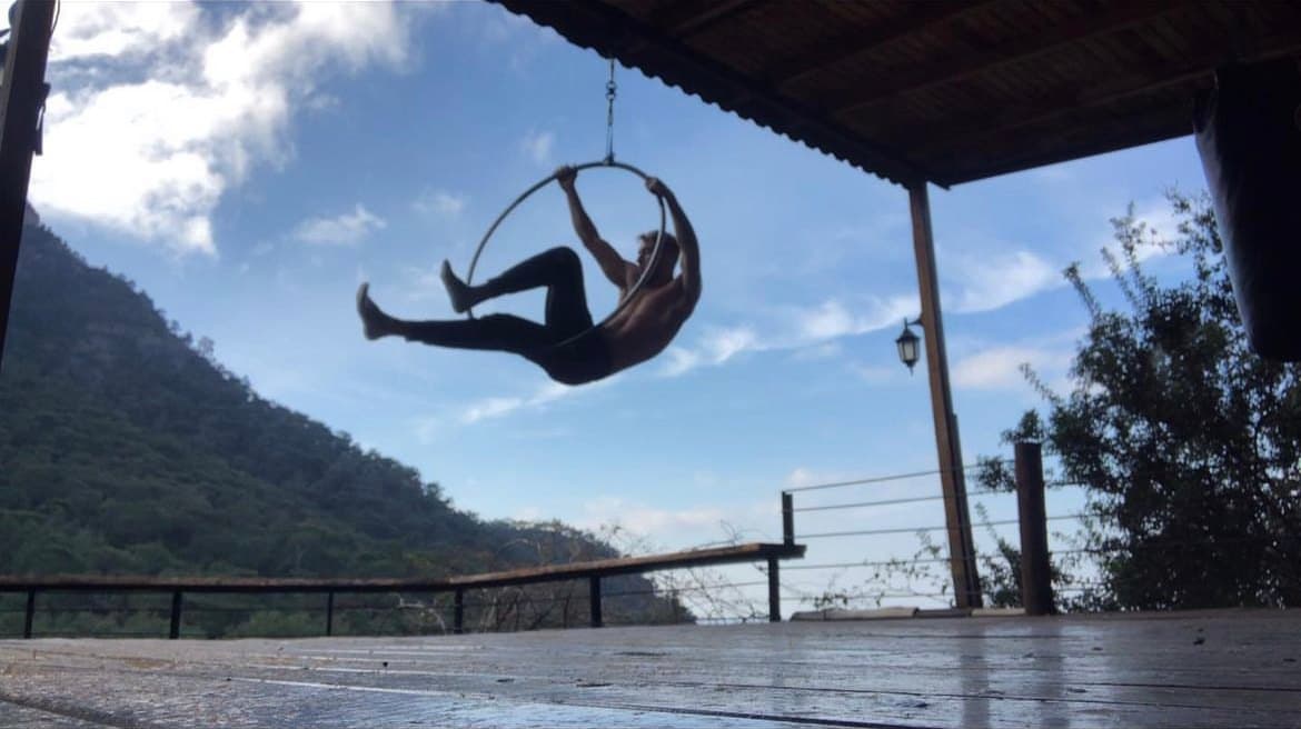 Kabak Koyu'nda ahşap bir terasta, dağ manzarası önünde aerial hoop üzerinde hareket