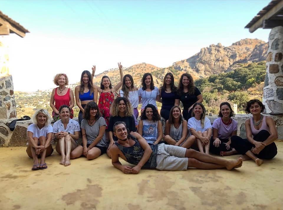 Dağ manzaralı bir terasta yoga eğitim programı katılımcılarıyla grup fotoğrafı; Türker en önde yerde uzanıyor