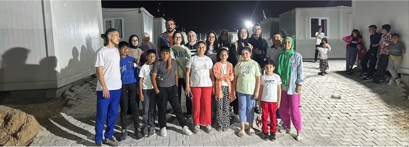 Akşam, konteynerlerin arasında çocuklar ve yetişkinlerle toplu fotoğraf