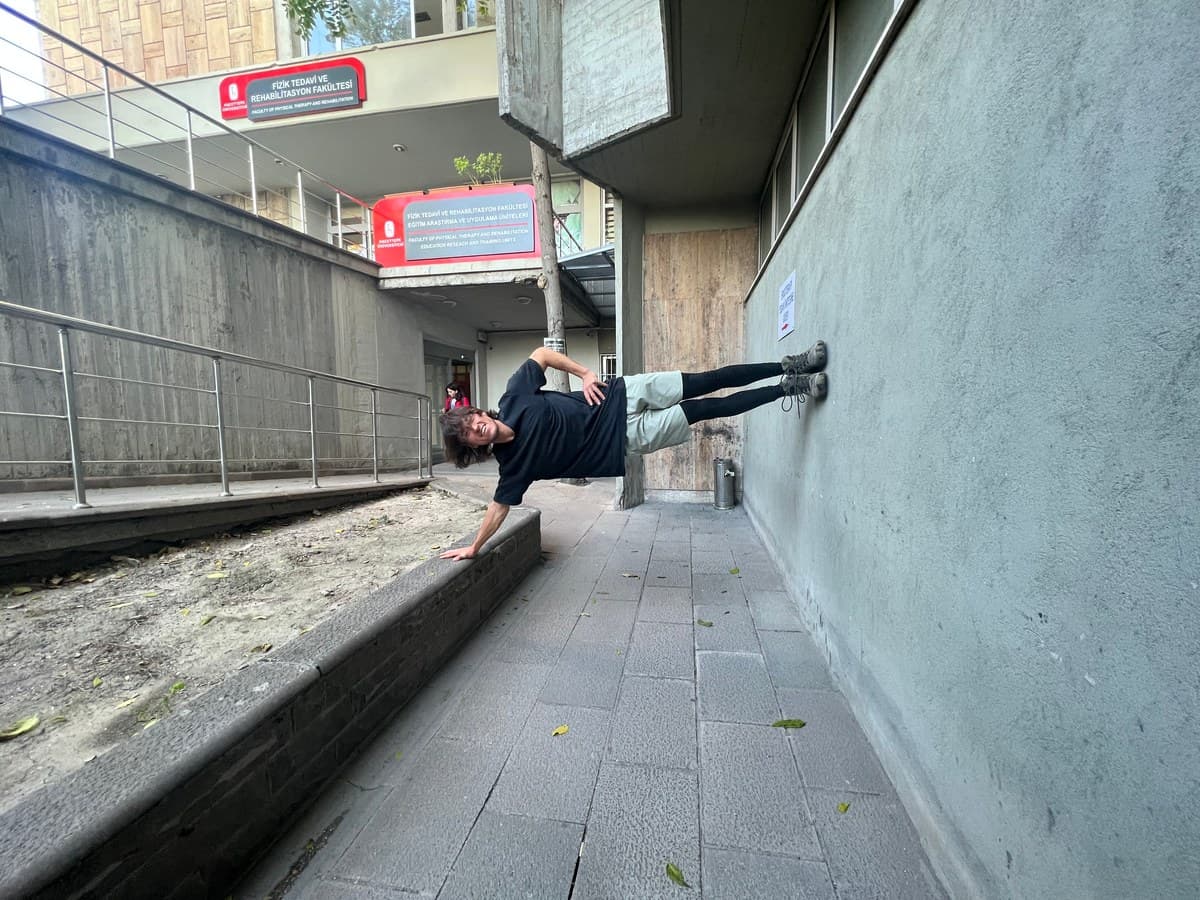 Türker bir binanın duvarında yan denge pozunda, kampüste