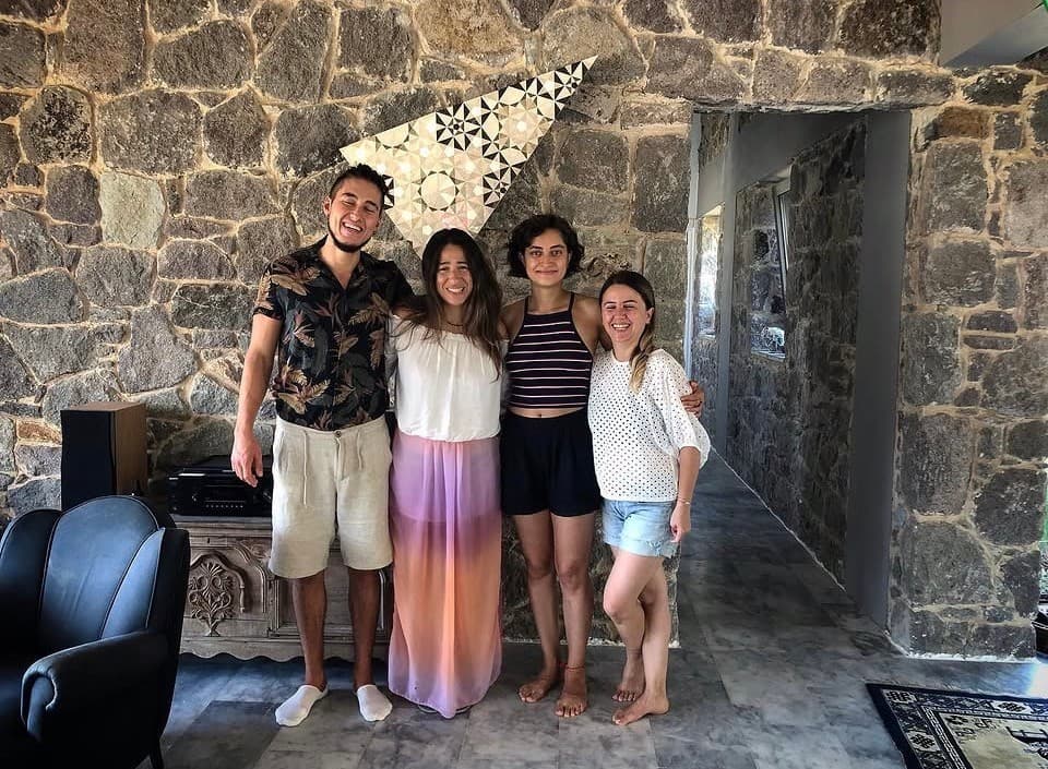 Taş duvarlı bir salonda Türker ve üç kişi yan yana gülümserken